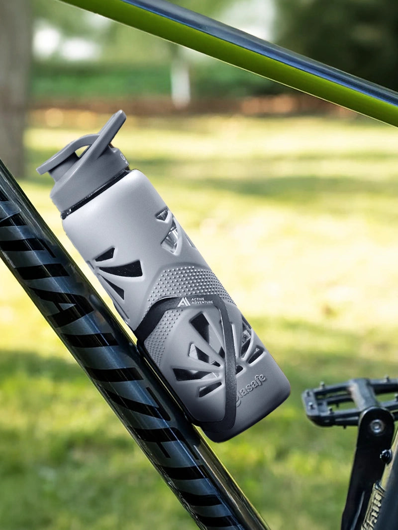Gray water bottle attached to a bicycle frame outdoors.